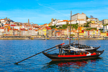 Wall Mural - Traditional boat on a Douro river with a picturesque Porto cityscape in the background. City features colorful buildings and historic architecture, creating a vibrant and scenic view of Portugal