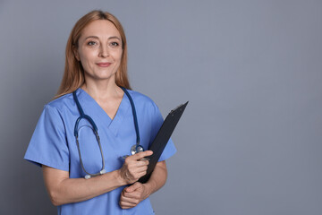 Wall Mural - Doctor with stethoscope and clipboard on gray background