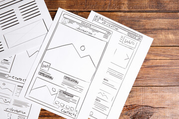 Leinwandbilder - Developing UI design. Sketches of website wireframes on wooden table, top view