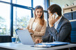 © NanSan - A businessman and woman sit at a modern office table, smiling and discussing a new project or business startup. They collaborate with a laptop, focusing on strategic planning and teamwork
