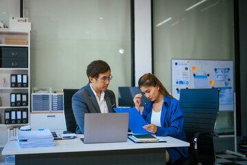 Wall Mural - A stressed businessman and woman sit at a desk, overwhelmed by business challenges. They discuss problems,financial pressures, and strategy, seeking solutions to manage work, deadlines, and economic