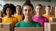 © Kunalai - A group of women in colorful shirts stand behind cardboard boxes, smiling confidently, representing teamwork and collaboration in a community setting.