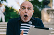 © BullRun - Amazed senior man using tablet on stairs in park