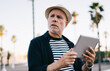 © BullRun - Pensive mature man using tablet on sidewalk