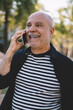 © BullRun - Delighted aged man speaking on cellphone in street
