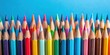 © InspireStock Gallery - A vibrant collection of sharpened colored pencils arranged in a neat row against a bright blue background