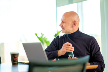 Wall Mural - Executive businessman sitting at the office desk and using his laptop