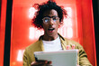 © BullRun - Expressive young curly male in eyewear holding digital tablet connected to 20s shocked with news from social media, stressed man blogger feeling anger about messages getting on touchpad outdoors