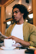 © BullRun - Bewildered man reading newspaper while drinking coffee in cafe