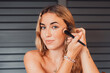 © Daniel - Portrait of one beautiful young girl making up and preparing herself making beauty morning routine. Blonde woman looking at camera doing skin care.