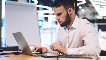 Fototapete - Caucasian male employee reading web information on browsed site survey during productive working process at office table, skilled businessman using 4g internet for making online banking and booking