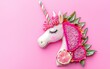 © Marina - A magical unicorn made with dragon fruit for the face and a candy cane slice for the horn, on a pastel pink background