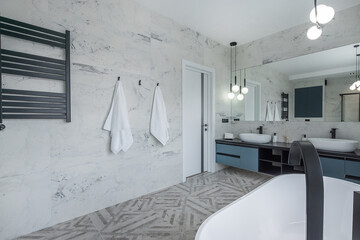 Stylish bathroom design decorated with grey tiles. Panoramic mirror, elegant lamps.