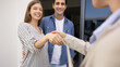 © fizkes - Happy couple of new homeowners shaking hand with realtor woman, insurance agent at entrance into new house, giving handshake to real estate consultant, smiling, laughing
