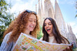 © CarlosBarquero - Young only women friend looking travel map in hands in front of Sagrada Familia in Barcelona. Beautiful caucasian girls at European city enjoying vacation happy and smiling. Funny tourism smile people