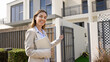 © fizkes - Happy positive professional realtor woman welcoming to apartment for rent or house for sale, pointing hand at open gate, looking at camera, smiling. Successful real estate agent outdoor portrait