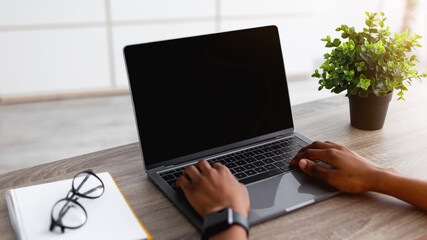 Poster - Unrecognizable black woman with laptop using new shopping website at home, mockup for design. Closeup of young Afro lady buying goods in web store, indoors. Modern technologies in everyday life