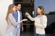 © fizkes - Confident female professional realtor woman giving key to couple of customers, offering rental to happy young husband and wife, meeting with new property owners at doorstep