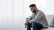 © Prostock-studio - Pain, sad, exhausted face looking concerned, worried and thoughtful, human emotions, facial expression, depression. Unhappy young european man sit in living room interior, think about problems