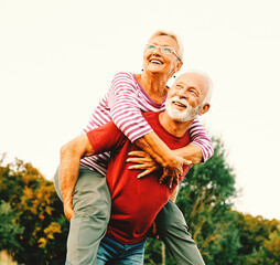 Wall Mural - woman man outdoor senior couple happy lifestyle retirement together smiling love piggyback active ma