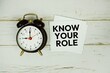 © may1985 - Know Your Role text message on sticky note with alarm clock on wooden background
