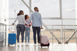 © Prostock-studio - Back rear view of black dad, mom and girl getting ready for flight. Loving family standing at departure lounge with suitcases waiting for the aircraft arrival, looking at plane flying. Free copy space