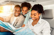 © Prostock-studio - Cheerful African American Family Looking At Road Map Sitting In Car. Parents And Daughter Choosing Destination For Summer Road Trip Together. Local Tourism Concept. Selective Focus