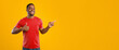 © Prostock-studio - Look There. African American Guy Pointing Finger Aside And Gesturing Thumbs Up Advertising Your Text Standing Over Yellow Studio Background. Man Showing Copy Space And Like Gesture. Panorama