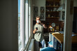 © Marko Geber - Man drinking coffee and using smartphone in sunny kitchen