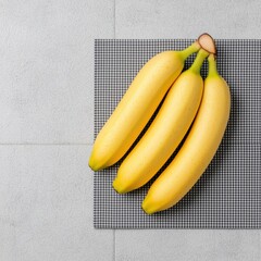 Wall Mural - Fresh Yellow Bananas on Gray Checkered Surface in Bright Light