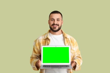Wall Mural - young man holding laptop with blank screen on green background. mockup for design