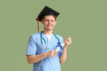 Wall Mural - Happy male medical graduate with diploma and stethoscope on green background