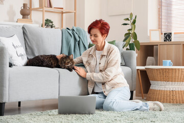 Wall Mural - Beautiful happy mature woman with cute cat and laptop sitting at home