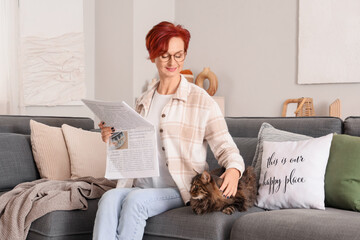 Wall Mural - Beautiful happy mature woman with cute cat and newspaper sitting on sofa at home