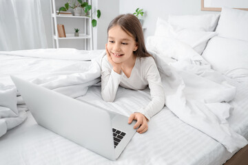 Wall Mural - Cute girl watching cartoons on laptop in bedroom