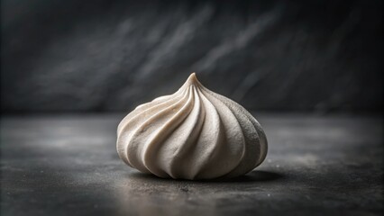Aufkleber - A single, delicately swirled meringue rests on a dark surface, a study in texture and light
