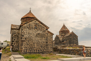 Wall Mural - A stone building with a cross on top. A woman is standing in front of it. The building is old and has a Gothic style