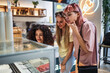 © Koldo_Studio - Three young women choosing ice cream flavors in a modern ice cream shop