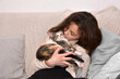 © zdravinjo - Young girl sitting on the sofa hugging and kissing her kitten. Friendship of child and animal. Keeping pets at home, care and love of animals concept.