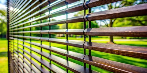 Aufkleber - A close-up view of a wooden slat fence with a blurred background of green grass and trees, creating a sense of depth and privacy.