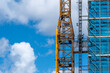 © yaqui_villegas - A striking close-up of a crane structure highlights the intricate details of construction machinery against a beautiful blue sky adorned with fluffy clouds.