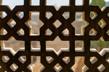 Wall Mural - A window with a stone frame that has a pattern of small squares. The window is open, and the view outside is obscured by the frame. Scene is somewhat mysterious