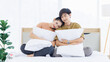 © Bangkok Click Studio - Portrait of young lovely sweet attractive asian happy couple love posing to camera smiling hugging pillow sitting on white bed in bedroom at home good time romantic together Valentine's day concept.