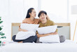 © Bangkok Click Studio - Portrait of young lovely sweet attractive asian happy couple love posing to camera smiling hugging pillow sitting on white bed in bedroom at home good time romantic together Valentine's day concept.