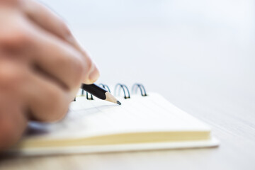 Poster - Closeup of male hand writing to notepad on blur background