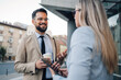 © Zamrznuti tonovi - Businessman holding coffee and tablet talking to businesswoman outdoors