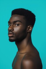 Wall Mural - A man with a shaved head and a beard is standing in front of a blue background. The man's face is the main focus of the image, and he is looking directly at the camera