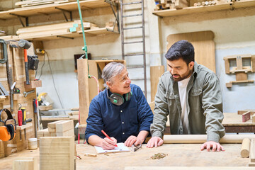 Wall Mural - Young apprentice learning woodworking skills from experienced craftsman