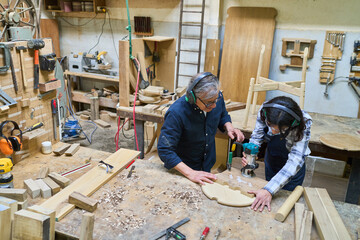 Wall Mural - Older mentor guiding young apprentice in a busy woodworking shop