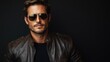 © Blackmint Studio - Stylish man wearing a leather jacket and aviator sunglasses poses confidently against a dark background in an urban setting during the day